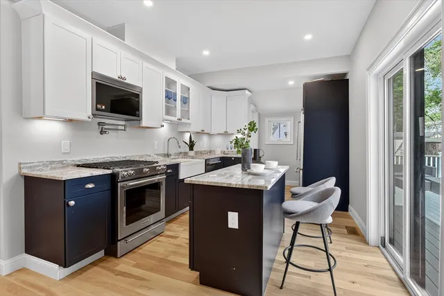 a kitchen with stainless steel appliances granite countertop a stove top oven a sink dishwasher a dining table and chairs with wooden floor