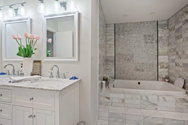 a bathroom with a tub sink and mirror