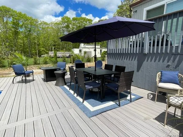a view of a roof deck with table and chairs under an umbrella with wooden floor