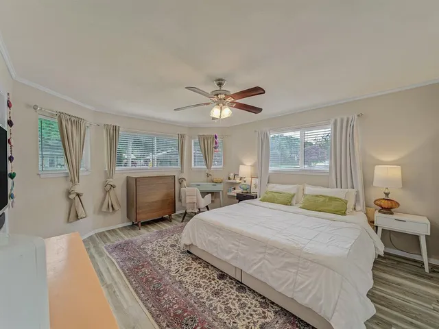 a bedroom with a large bed a chandelier and windows