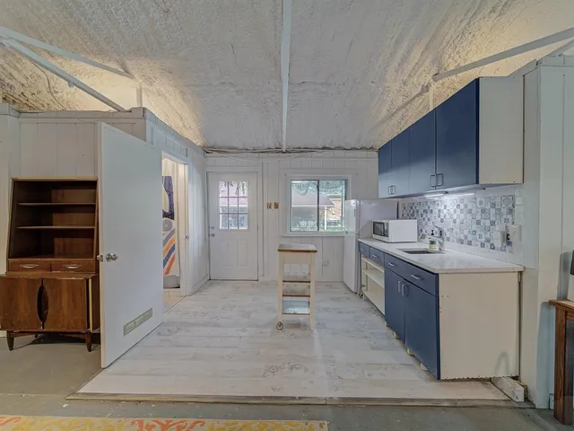 a kitchen with stainless steel appliances kitchen island granite countertop a refrigerator stove oven and white cabinets with wooden floor