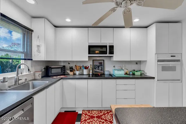 a kitchen with stainless steel appliances kitchen island granite countertop a sink a stove top oven a counter space and cabinets