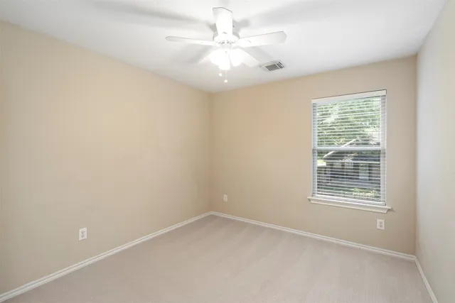 an empty room with windows and ceiling fan
