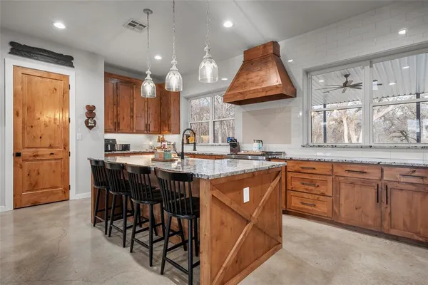 a kitchen with stainless steel appliances granite countertop a table chairs sink and cabinets