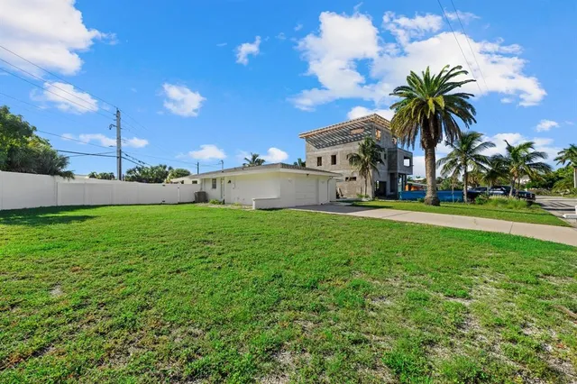 a view of a house with a big yard plants and palm trees