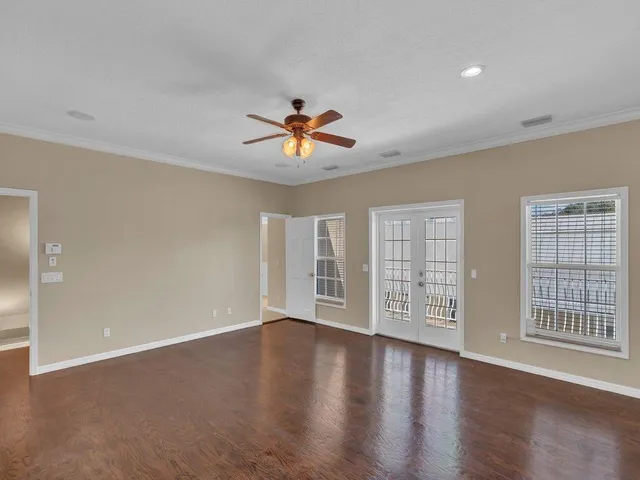 a view of an empty room with a window and wooden floor