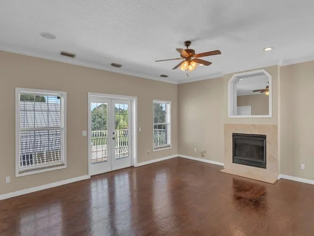 a view of an empty room with window and wooden floor