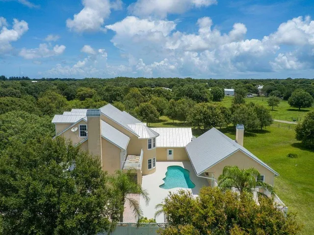 an aerial view of a house with a yard and lake view in back