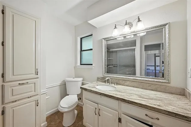 a bathroom with a granite countertop toilet a sink and a large mirror