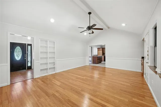 a view of an empty room with a window and wooden floor