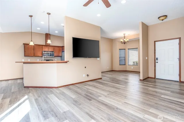 a view of a kitchen with kitchen island a counter top space stainless steel appliances and wooden floor