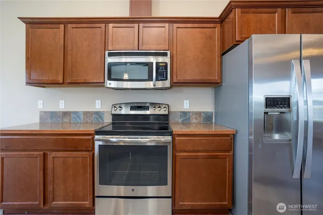 a kitchen with stainless steel appliances granite countertop a refrigerator stove and microwave