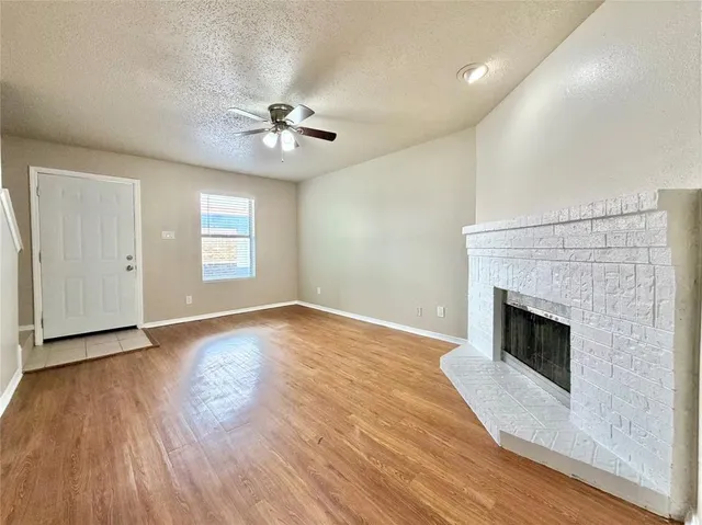 an empty room with wooden floor fireplace and windows
