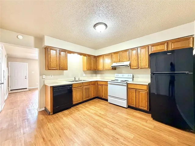 a kitchen with granite countertop a refrigerator stove top oven and sink