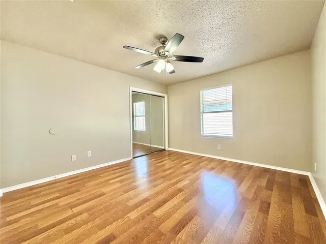 a view of an empty room with window and wooden floor