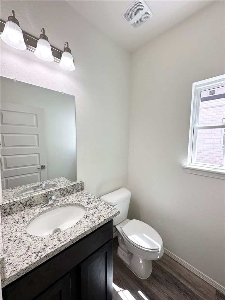 959 South Rupple Road, Unit 4 Fayetteville, AR 72704 - Photo 21 of 25 This bathroom features a vanity with a granite countertop and a white sink, a toilet, and wood-look flooring