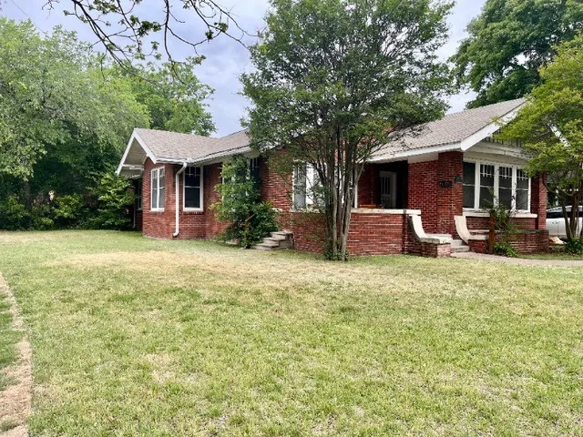a front view of house with yard and trees around