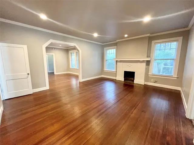 an empty room with wooden floor fireplace and windows