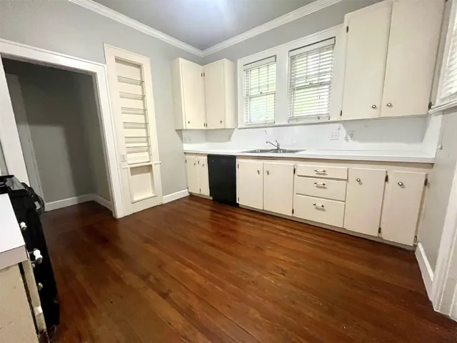 a kitchen with granite countertop white cabinets and wooden floor