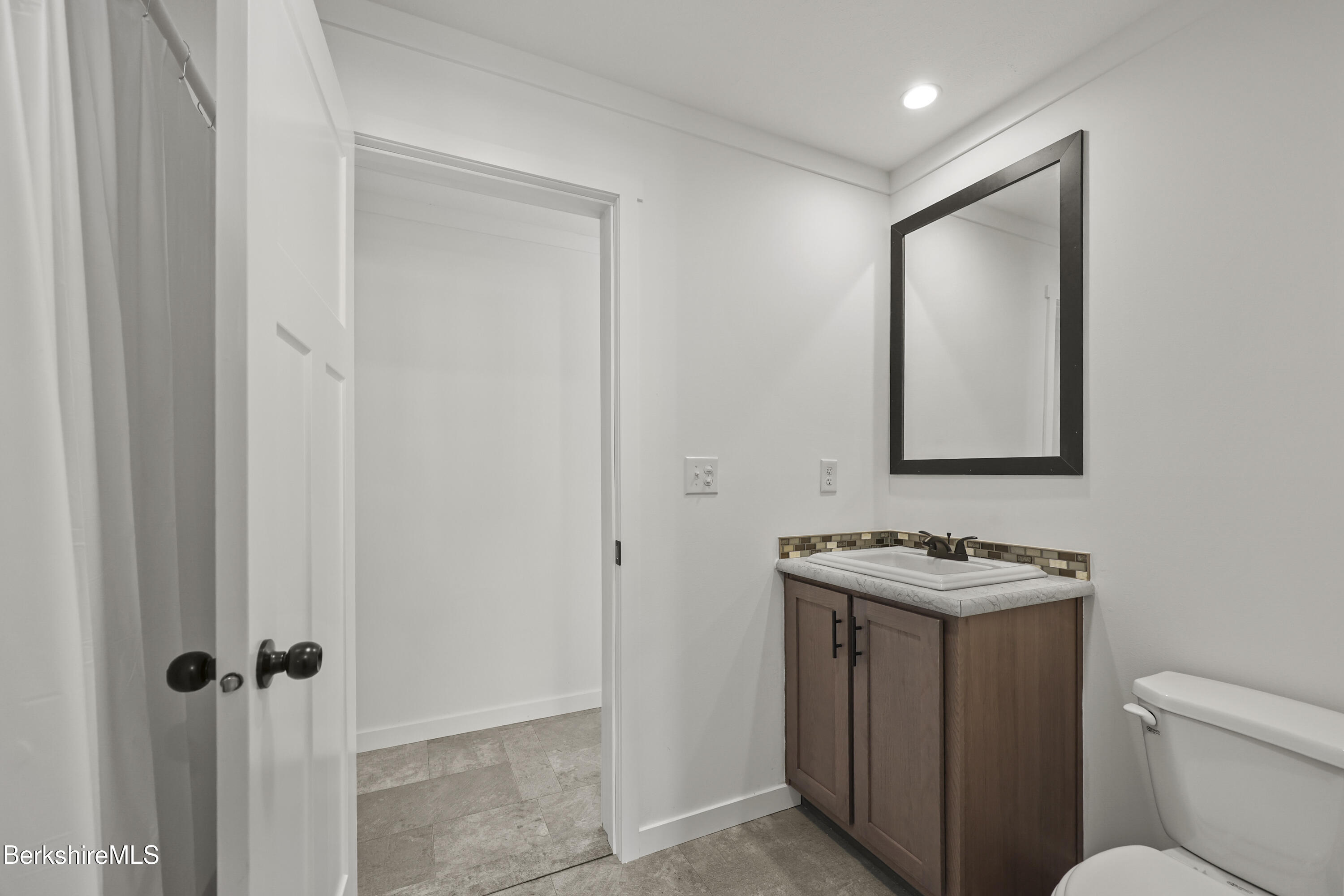 395 Cheshire Road, Unit 102 Pittsfield, MA 01201 - Photo 27 of 28 a bathroom with a toilet sink vanity and mirror