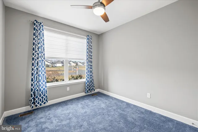 an empty room with a ceiling fan and a window