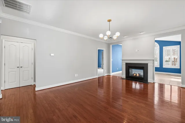 an empty room with wooden floor fireplace and chandelier