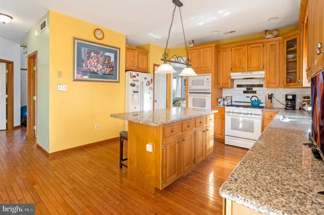 a kitchen with stainless steel appliances granite countertop a refrigerator a oven a sink with island and chairs