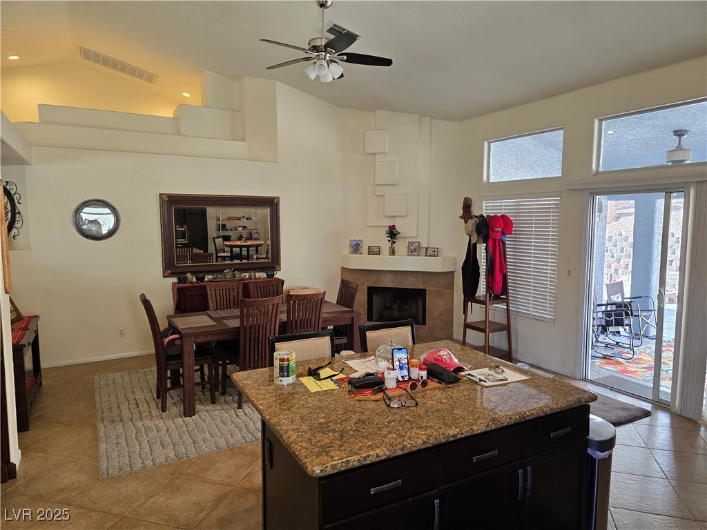853 Rusty Anchor Way Henderson, NV 89002 - Photo 11 of 76 Kitchen with high vaulted ceiling, a tiled fireplace, dark cabinetry, and light tile patterned floors.