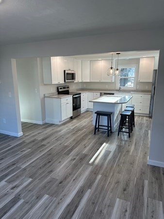 a kitchen with kitchen island granite countertop a sink cabinets and wooden floor