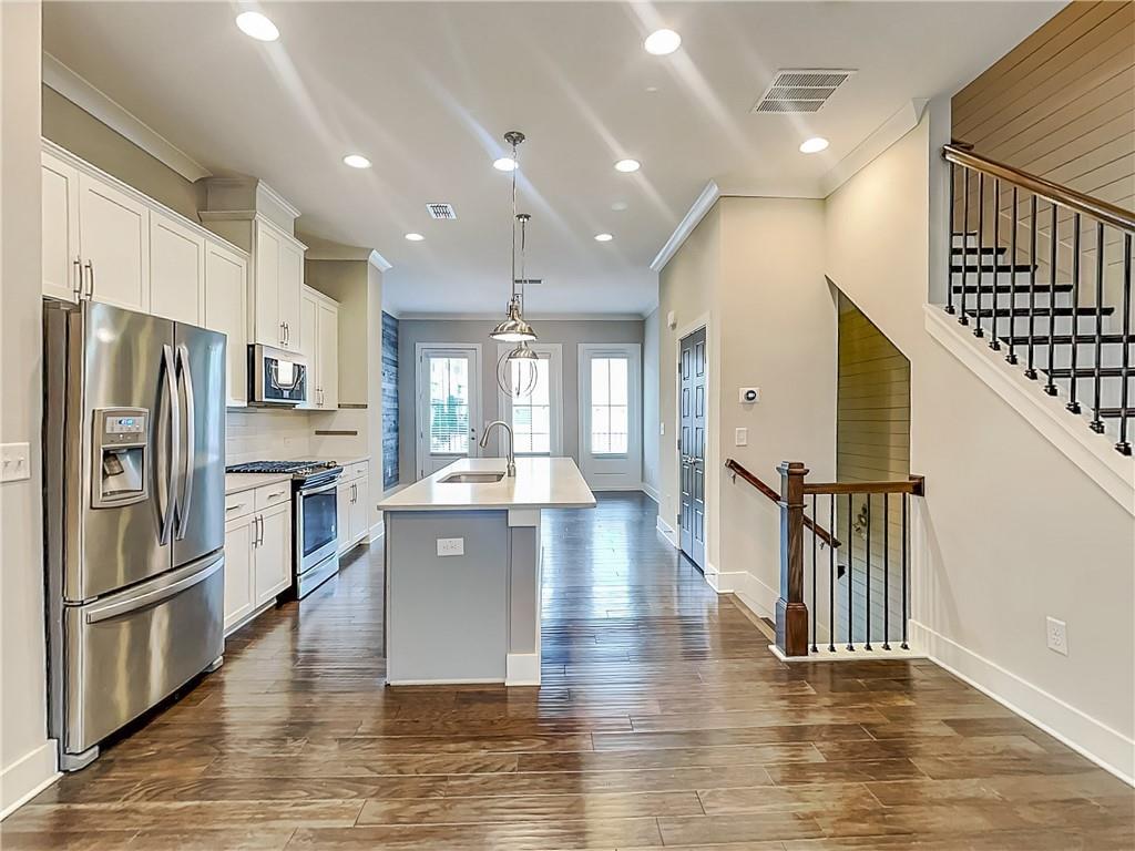 a large kitchen with cabinets wooden floor and stainless steel appliances