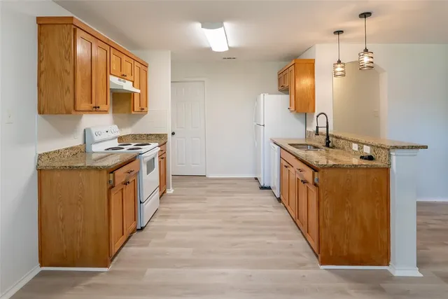 a kitchen with granite countertop a sink and a wooden floor