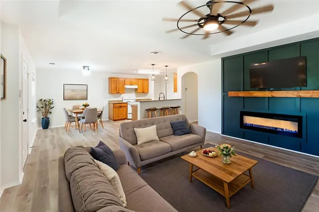 a living room with furniture a flat screen tv and kitchen view