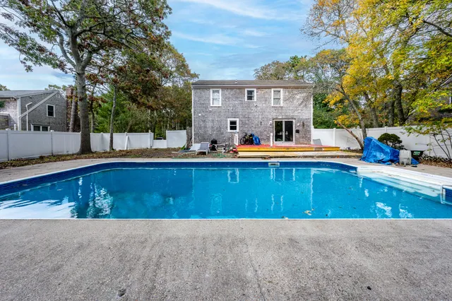 a view of swimming pool with outdoor seating and house in the background