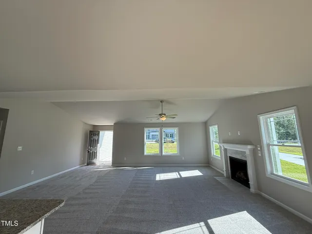 a view of an empty room with a window and fireplace