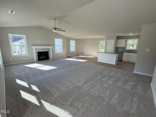 a view of a livingroom with a fireplace a chandelier and windows