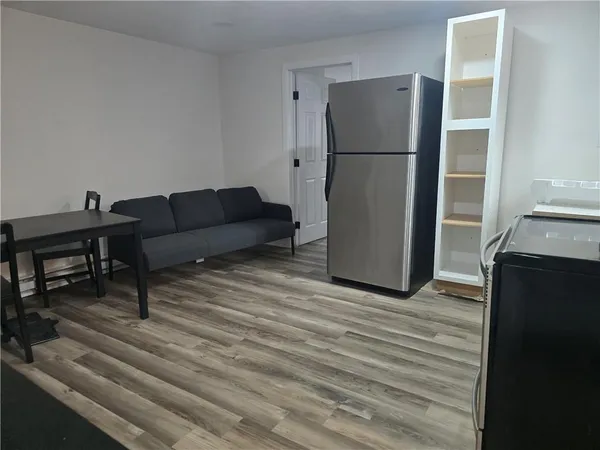 a living room with furniture and a refrigerator