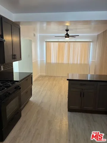 a kitchen with granite countertop stainless steel appliances a stove a sink a refrigerator and wooden floor