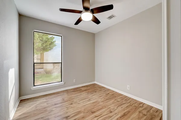an empty room with a window and wooden floor