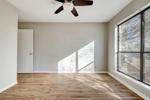 a view of an empty room with wooden floor and windows