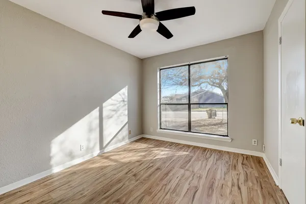 an empty room with wooden floor and windows