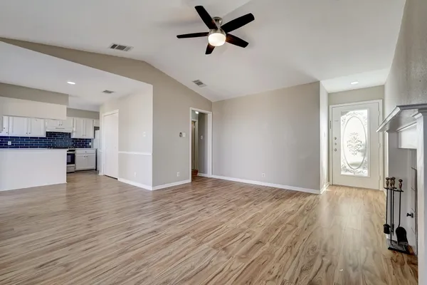 a view of empty room with wooden floor and ceiling fan