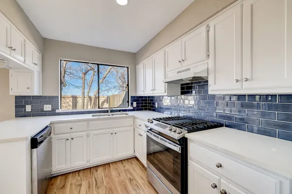 a kitchen with granite countertop white cabinets and white appliances