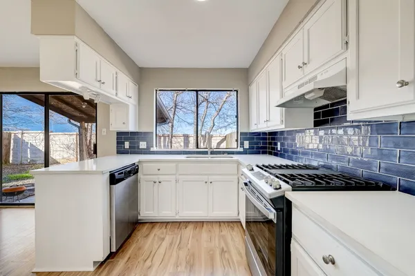 a kitchen with cabinets appliances a sink and a window