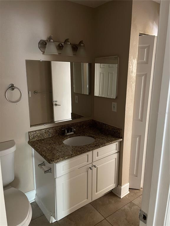 4512 Commander Drive, Unit 1725 Orlando, FL 32822 - Photo 13 of 17 a bathroom with a granite countertop sink toilet and mirror