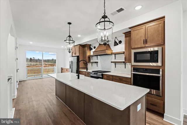 a kitchen with a sink stainless steel appliances and wooden floor