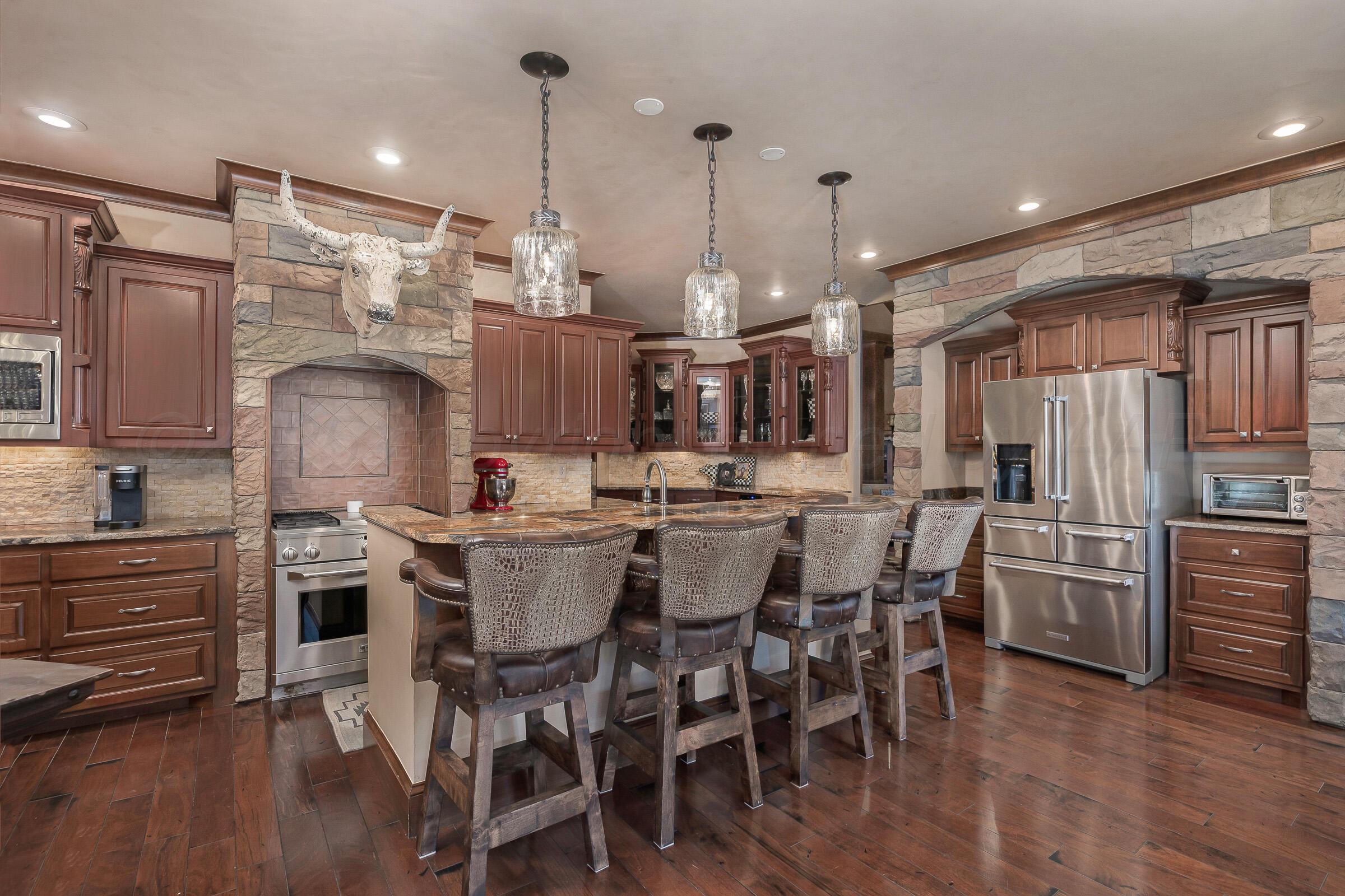 19551 Chaparral Road Canyon, TX 79015 - Photo 11 of 42 a kitchen with stainless steel appliances kitchen island granite countertop a table chairs and wooden floor