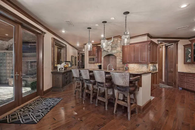 a kitchen with stainless steel appliances kitchen island granite countertop a table chairs and a wooden floor