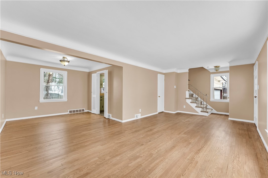 4693 Liberty Road South Euclid, OH 44121 - Photo 6 of 33 Unfurnished living room with healthy amount of natural light, stairs, light wood-style floors, and ornamental molding