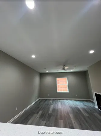 a view of an empty room with wooden floor and windows