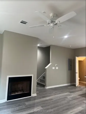 a view of an empty room with wooden floor and a fireplace